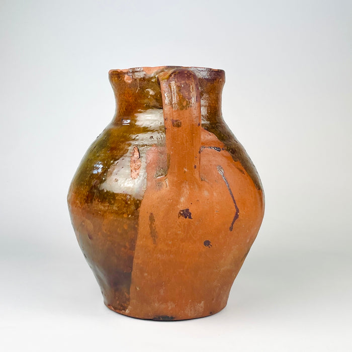 Spanish orza storage jar, with a dark brown glazed cavity, circular throwing rings and a naturally irregular rim. The nineteenth century terracotta vessel was made for domestic storage and now works as an antique pottery vase for dried branches, Mediterranean decor or wabi sabi decor.