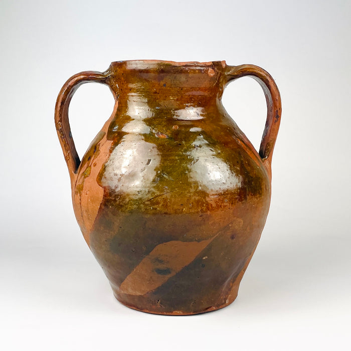 Antique Spanish glazed terracotta vase from nineteenth century Castile, formed as a traditional two handled orza pottery jar. The rounded red clay body has a short neck, open mouth, amber brown glaze across the upper section, exposed terracotta below, and age worn patina suited to Mediterranean decor or farmhouse decor.