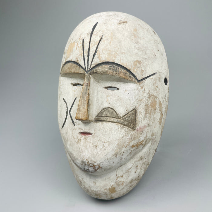 African carved wood tribal mask with white pigment, inspired by ceremonial masks from the Fang and Kwele peoples of Central Africa, shown upright with stylized features and drilled holes for wall mounting or decorative use in rustic interiors.