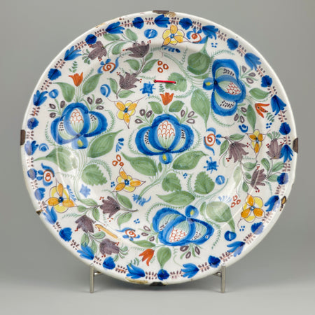 Antique Manises ceramic plate with vibrant polychrome floral design, shown in full view on neutral background, showcasing 19th-century Spanish craftsmanship and original iron wall mount for Mediterranean wall decor.