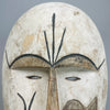 African mask with white kaolin-style surface and incised tribal face details, drawing visual influence from Fang and Kwele ceremonial traditions, perfect for interior styling or decorative collections of folk art.