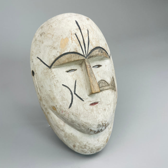 Vintage African tribal mask with ceremonial white pigment and carved wood design, showcasing abstract facial geometry, ideal for rustic home styling, wabi-sabi collections, or collectors of African ethnographic art pieces.