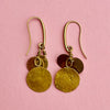 Pair of hammered disc drop earrings with reflective golden surfaces catching the light. Their handcrafted finish and comfortable nickel-free hooks make them suitable as everyday earrings, minimalist. Ideal for summer jewelry styling, minimalist wardrobes, and Mediterranean-inspired accessories. 