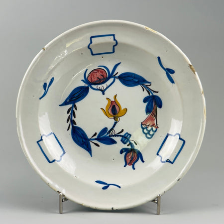 Antique Manises ceramic plate featuring hand-painted floral motif in cobalt blue, red, and yellow, photographed front-on for use as Spanish faience wall decor or Mediterranean tabletop accent.
