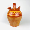 Antique terracotta water jug from northern Spain, dating to the early 20th century, made in the traditional botijo form with a rounded body, arched handle, wide filling mouth, and narrow drinking spout. The upper half is glazed in a warm chestnut brown and hand painted with yellow scalloped decoration, while the lower body remains unglazed red clay. This Spanish folk pottery vessel can be styled in Mediterranean decor, farmhouse decor, and vintage home decor.