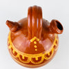 Antique terracotta water jug from Spain with hand painted folk decoration and a classic two opening botijo design. The larger mouth was intended for filling, the smaller spout for pouring or drinking, and the porous clay body helped keep water cool. The decorative shoulder band is painted in yellow over glossy brown glaze, while the lower half retains its raw terracotta finish. This northern Spanish ceramic vessel works naturally in Mediterranean decor, farmhouse decor, and vintage home decor.