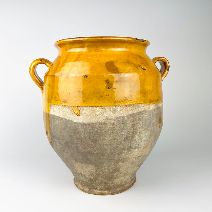 Antique French confit pot dating to the 19th century, made from wheel-thrown terracotta with a warm mustard yellow glaze over the upper body and raw pale clay below. Documented measurements are 26.6 cm high, 26 cm wide handle to handle, and 2.6 kg, demonstrating the substantial scale of this French pottery jar.