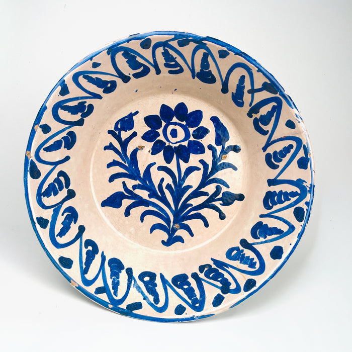 Antique Spanish Fajalauza lebrillo bowl from Granada, dating to the 19th century, made in tin glazed terracotta with a warm cream-white ground and bold cobalt blue decoration. The center shows a hand painted floral spray, while the wide inner wall carries a repeating blue border. This Granada pottery bowl works as a decorative bowl, table centerpiece, or wall hanging ceramic for Mediterranean decor, rustic home decor, and vintage home decor.
