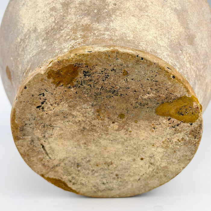 Antique French confit pot held to demonstrate its substantial scale, measuring 26.6 cm high and 26 cm wide handle to handle with a weight of 2.6 kg. The large rounded terracotta body, intact twin handles, mustard yellow glazed upper section and tapered raw-clay base create a strong sculptural presence for French country decor or farmhouse decor.