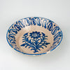 Spanish Granada lebrillo bowl in antique Fajalauza earthenware, decorated with a stylized blue flower and branching foliage in the center, surrounded by a rhythmic blue border painted freehand around the interior wall. The cream-white glaze shows light crazing and age wear, with small chips along the rim. This antique Spanish pottery bowl fits Mediterranean decor, farmhouse decor, and decorative wall bowl collections focused on regional ceramic traditions.