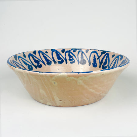 Antique Fajalauza bowl from Granada, Spain, with a floral motif painted by hand in cobalt blue over a pale tin glazed ground. The bowl has a generous 31.5 cm width, a shallow-deep lebrillo profile, and visible terracotta beneath small glaze losses at the rim and interior. This Spanish pottery piece can be styled as a centerpiece bowl, decorative bowl, or wall display ceramic in rustic home decor, wabi sabi decor, and vintage home decor.