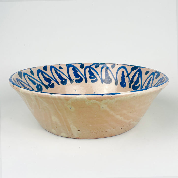 Antique Fajalauza bowl from Granada, Spain, with a floral motif painted by hand in cobalt blue over a pale tin glazed ground. The bowl has a generous 31.5 cm width, a shallow-deep lebrillo profile, and visible terracotta beneath small glaze losses at the rim and interior. This Spanish pottery piece can be styled as a centerpiece bowl, decorative bowl, or wall display ceramic in rustic home decor, wabi sabi decor, and vintage home decor.