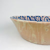 Spanish antique decorative bowl from Granada, identified as a Fajalauza lebrillo, with hand painted blue floral ornament on a pale tin glazed surface. The central flower and scrolling foliage are framed by a repeating border of curved blue strokes and small dot-like accents, creating strong radial balance. This antique Spanish pottery bowl fits farmhouse decor, vintage home decor, Mediterranean decor, and collections of blue and white ceramic wall art.