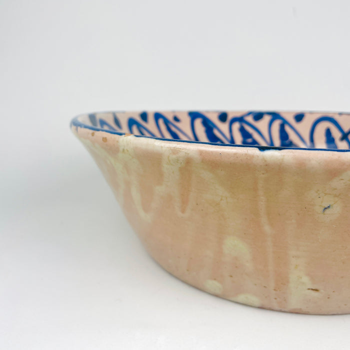 Spanish antique decorative bowl from Granada, identified as a Fajalauza lebrillo, with hand painted blue floral ornament on a pale tin glazed surface. The central flower and scrolling foliage are framed by a repeating border of curved blue strokes and small dot-like accents, creating strong radial balance. This antique Spanish pottery bowl fits farmhouse decor, vintage home decor, Mediterranean decor, and collections of blue and white ceramic wall art.
