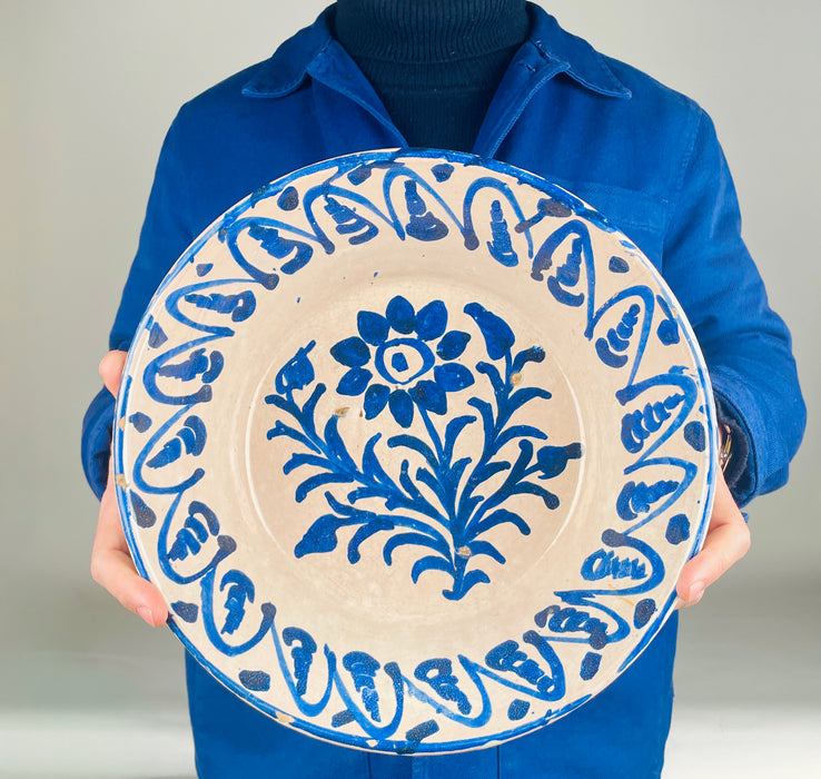 Spanish antique lebrillo bowl in Fajalauza pottery from Granada, hand painted in cobalt blue on a cream-white tin glazed surface. The broad open basin, floral center, and repeating border pattern are characteristic of Granada ceramic traditions, while rim fritting and glaze wear confirm age and use. This antique and vintage decorative bowl suits farmhouse decor, Mediterranean decor, and wall hanging ceramic displays built around historic Spanish pottery.