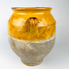  Detail of an intact applied loop handle on the antique French confit pot, showing the hand-shaped terracotta construction, mustard yellow glaze, fine crazing, small glaze losses and age-related rubbing. The flared rim and rounded shoulder are also visible, highlighting the handmade character of this 19th century French pottery and its authentic farmhouse decor patina.