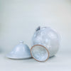 Large French decorative bowl with an urn shaped silhouette, white ceramic surface, twin handles, and a domed lid resting above a rounded body on a flared pedestal. The restrained monochrome finish and naturally rubbed glaze work with wabi sabi decor, organic modern decor, and Mediterranean decor.