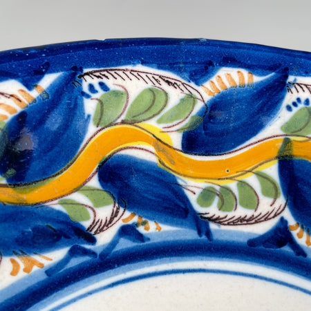 Close-up of yellow bird motif hand-painted in central medallion, surrounded by blue leaf flourishes, representing regional Iberian ceramic tradition ideal for folk art collectors and wall-mounted display.