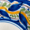 Detail of scalloped rim and raised brushwork in blue, green, and ochre glaze showing intricate craftsmanship typical of antique Manises ceramics, captured at a diagonal angle for pottery collectors.