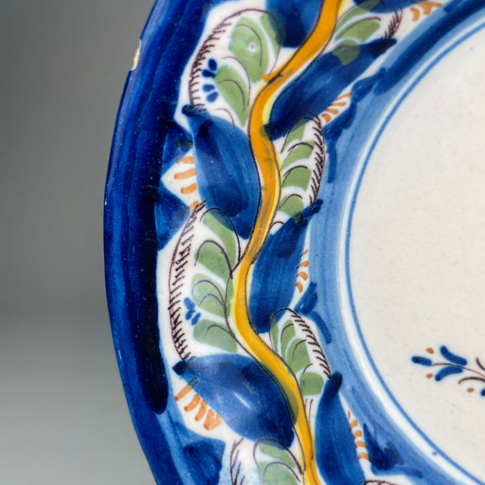 Full frontal view of Manises pottery plate from late 19th century, showcasing yellow bird design at center, surrounded by vibrant cobalt blue and green border, styled for use in Spanish revival decor or eclectic ceramic collections.