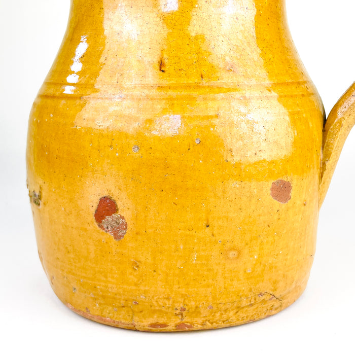 Antique earthenware jug from La Rioja with a rounded lower body, narrowed neck and wide mouth shaped into a clear pouring lip. The ochre glaze continues into the interior, where pronounced wheel-thrown rings remain visible, recording the handmade construction and giving this substantial Spanish pitcher a compelling folk pottery presence.