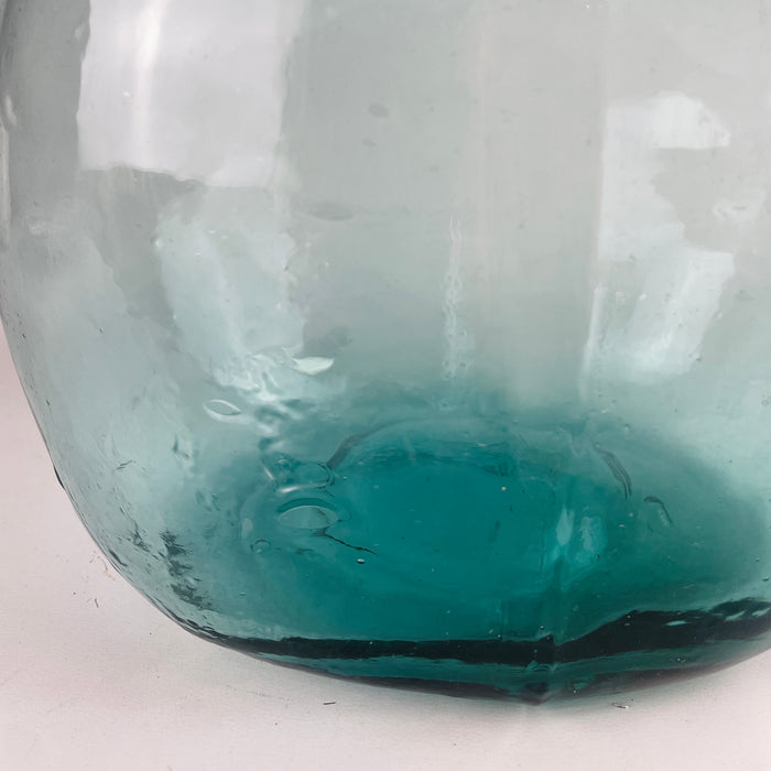 Spanish Viresa hand blown demijohn in luminous aqua blue glass, formed with a rounded balloon body and tall neck used historically for wine and liquid storage. The glass shows trapped bubbles, waviness, and thickness variation that support its handmade character, while the color suits Mediterranean decor, coastal decor, and rustic home decor.