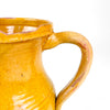 Late 19th century Spanish pottery pitcher from La Rioja, made in red earthenware and finished with a warm yellow glaze. The body displays wheel-turning marks, two shallow decorative bands, scattered glaze losses and firing variations, while the curved handle and shaped spout reflect the vessel’s original household function.