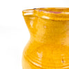Antique yellow terracotta jug from La Rioja with a stable cylindrical base, softly rounded shoulder and narrowed upper body. Its handmade spout and large looping handle provide a confident utilitarian profile, while the ochre glaze varies from deep golden yellow to paler honey tones across the aged wheel-thrown surface.
