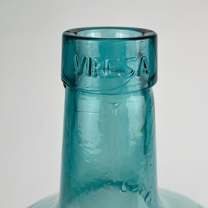 Vintage Spanish blue green glass demijohn with embossed Viresa neck, hand blown construction, and a classic wine carboy silhouette. The strong rounded form, visible melt lines, and handmade bubble inclusions give this bottle authentic character, making it a practical decorative vase for olive branches, dried stems, or standalone display.