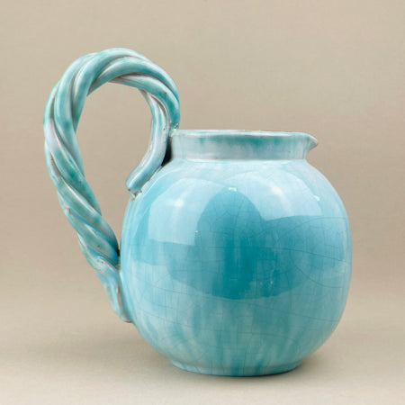 Turquoise ceramic pitcher with a twisted handle on a beige background. A mid-century Belgian studio pottery jug signed Alexander de Wemmel, finished in a glossy turquoise crackle glaze with tonal depth. The bold twisted rope handle adds sculptural impact, making this vintage ceramic ideal for collectors of modernist European pottery.