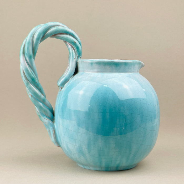 Turquoise ceramic pitcher with a twisted handle on a beige background. A mid-century Belgian studio pottery jug signed Alexander de Wemmel, finished in a glossy turquoise crackle glaze with tonal depth. The bold twisted rope handle adds sculptural impact, making this vintage ceramic ideal for collectors of modernist European pottery.