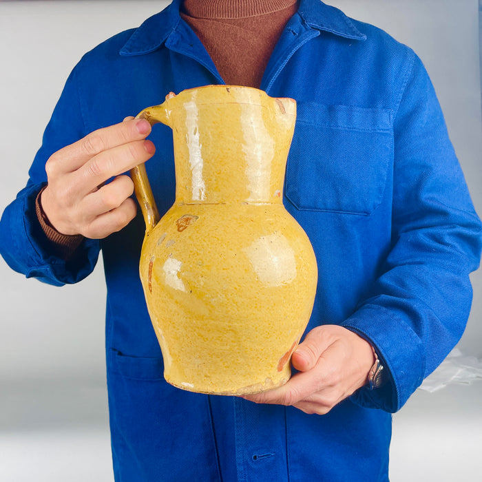 Nineteenth century Spanish terracotta pitcher sourced in Burgos, Castile, with a mellow yellow glaze and traditional jarra form. The handmade vessel has a sculptural rounded body, straight neck, and pinched spout, making it a compelling decorative object for antique kitchen pottery collections, Spanish country decor, and rustic home decor.