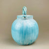 Ceramic vase with a textured surface on a beige background. Angle showing the jug displayed alongside other colorful ceramics, illustrating its compatibility with mid-century collections. The turquoise glaze contrasts beautifully with yellow and green tones, perfect for eclectic or modernist interiors.