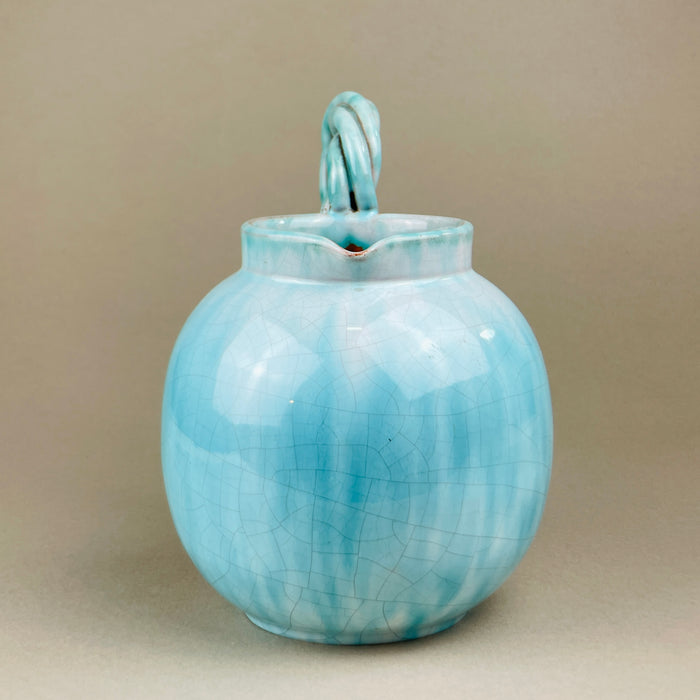 Ceramic vase with a textured surface on a beige background. Angle showing the jug displayed alongside other colorful ceramics, illustrating its compatibility with mid-century collections. The turquoise glaze contrasts beautifully with yellow and green tones, perfect for eclectic or modernist interiors.