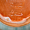 Close-up of a ceramic bowl with 'Made in Belgium' inscription. Bottom view highlighting the base with natural wear from age and handling. The “Alexander” signature remains visible, confirming authorship and adding collector value to this 1950s Belgian studio pottery jug.
