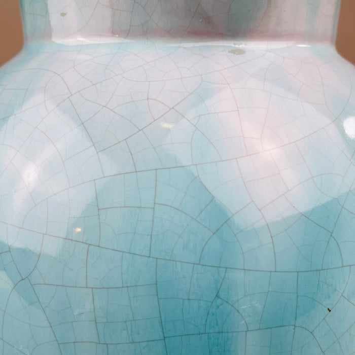 Close-up of a ceramic vase with a cracked glaze pattern. Close-up of the turquoise glaze on the jug’s surface, showing fine crackle lines and tonal variations. This hand-applied finish captures the artisanal quality typical of Belgian studio pottery from the 1950s, now highly collectible worldwide.