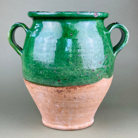 Antique French confit pot with bright green glaze and twin handles, shown front-facing against a neutral backdrop. The large terracotta body and glossy glaze evoke traditional French farmhouse pottery, perfect for rustic kitchen decor or Mediterranean interior styling.