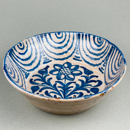 Hand-painted Spanish ceramic bowl with swirl and flower motif. Overhead view of Granada pottery showing Moorish-inspired pattern