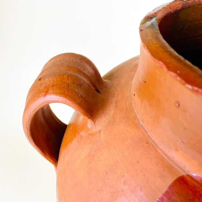 Antique Spanish pottery jar with a rounded terracotta body, wide cylindrical mouth, semi-glazed amber surface, and vertical glaze trails over red-orange clay. The large decorative vessel functions as a floor vase, sculptural clay pot, or statement terracotta jar for wabi sabi decor, organic modern decor, and rustic home decor.