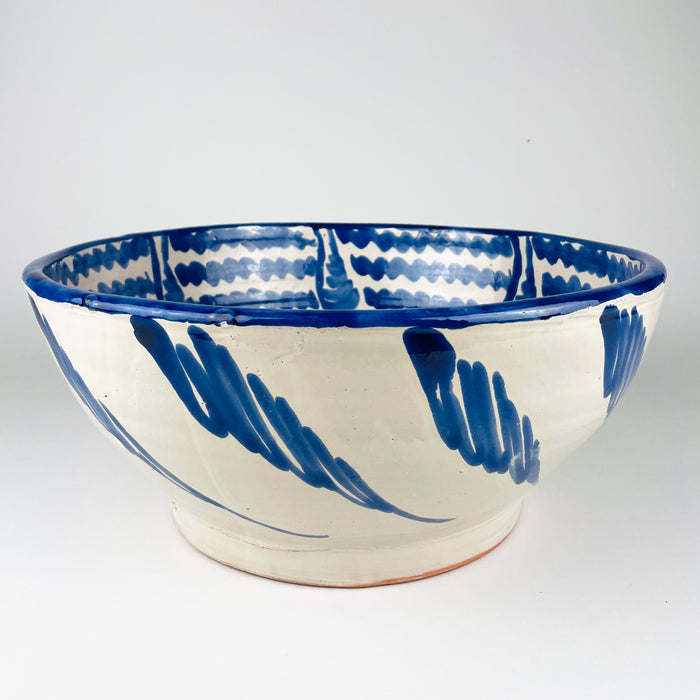 Substantial Granada pottery lebrillo with a broad circular rim, deep rounded walls and low foot, hand painted in cobalt blue and white. The exterior carries repeated flowing leaf-like brush motifs while the interior is densely patterned, giving this Spanish terracotta bowl equal presence as a fruit bowl, salad bowl or farmhouse decor centerpiece.