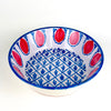 Red and blue Spanish Fajalauza lebrillo bowl designed by ROC Objects and produced in Granada in the traditional Fajalauza style. The piece combines a cream glazed interior, blue painted rim, red pomegranate motifs, and hand painted lattice pattern for use as a decorative bowl, wall hanging ceramic, or Mediterranean table centerpiece.