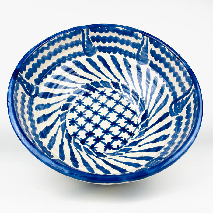 Large Spanish Fajalauza lebrillo bowl from Granada, handcrafted in glazed terracotta and painted in cobalt blue over a creamy white ground. The deep footed form combines sweeping exterior brushstrokes with an intricately decorated interior, creating a substantial serving bowl and decorative ceramic wall art piece for Mediterranean decor.