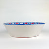 Spanish lebrillo bowl made in the traditional Fajalauza style, hand thrown in terracotta and hand painted with red fruit motifs, blue dotted arches, and a geometric blue lattice. This decorative Granada pottery bowl is suited to table centerpiece styling, wall bowl display, fruit presentation, and rustic home decor.