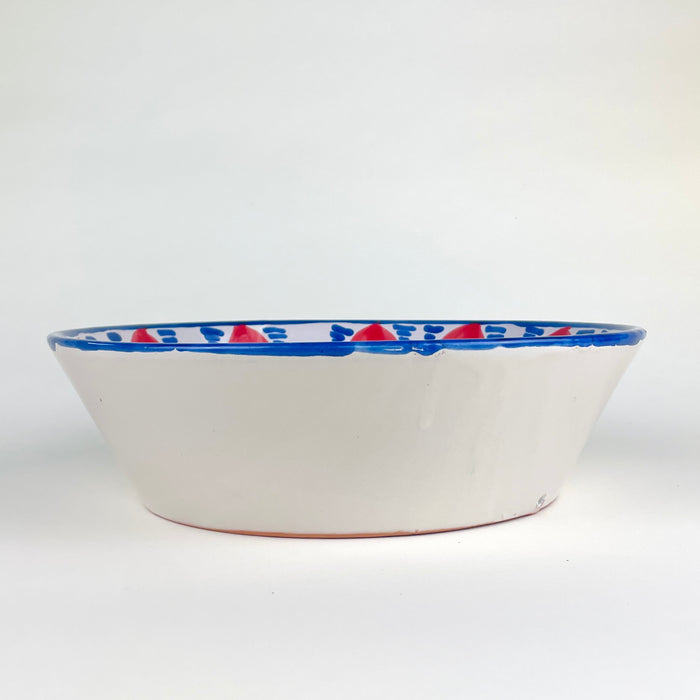 Spanish lebrillo bowl made in the traditional Fajalauza style, hand thrown in terracotta and hand painted with red fruit motifs, blue dotted arches, and a geometric blue lattice. This decorative Granada pottery bowl is suited to table centerpiece styling, wall bowl display, fruit presentation, and rustic home decor.