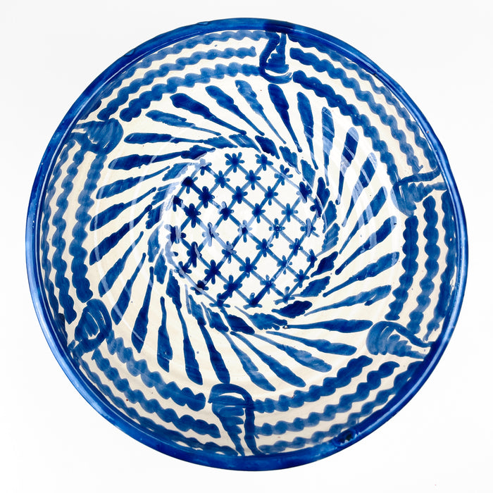 Traditional Fajalauza brushwork across the white glazed terracotta surface, with dense cobalt blue strokes forming leaves, scalloped bands and geometric ornament. Variations in pigment density, visible bristle marks and slight glaze irregularities confirm the handcrafted character of this Cerámica Los Arrayanes bowl from Granada, Spain.