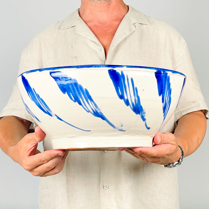 Flowing cobalt blue exterior brushwork on a white glazed Spanish terracotta lebrillo from Granada. The repeated tapering motifs curve around the substantial bowl and contrast with the denser interior decoration, giving the piece a strong graphic profile as a serving bowl, table centerpiece, decorative wall plate or Mediterranean decor accent.
