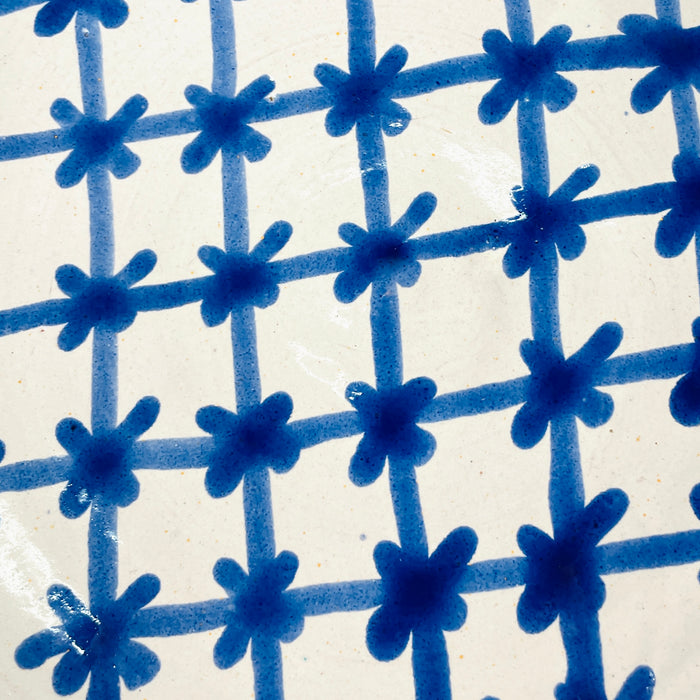 Thick cobalt blue rim and patterned interior of a large Spanish lebrillo bowl, with hand painted wavy bands and tapering botanical forms over a creamy white glaze. The deep Granada pottery form is suitable as a substantial serving bowl for fruit or salad and also includes pierced hanging holes for use as decorative ceramic wall art.