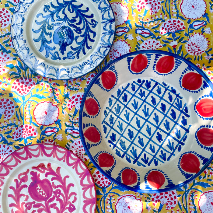 Hand painted Granada Fajalauza lebrillo bowl with a blue rim, red pomegranate border, and central blue lattice pattern on a cream glazed terracotta body. This contemporary Spanish pottery piece can be used as a decorative bowl, sculptural table centerpiece, or wall hanging ceramic in farmhouse decor and rustic home decor settings.