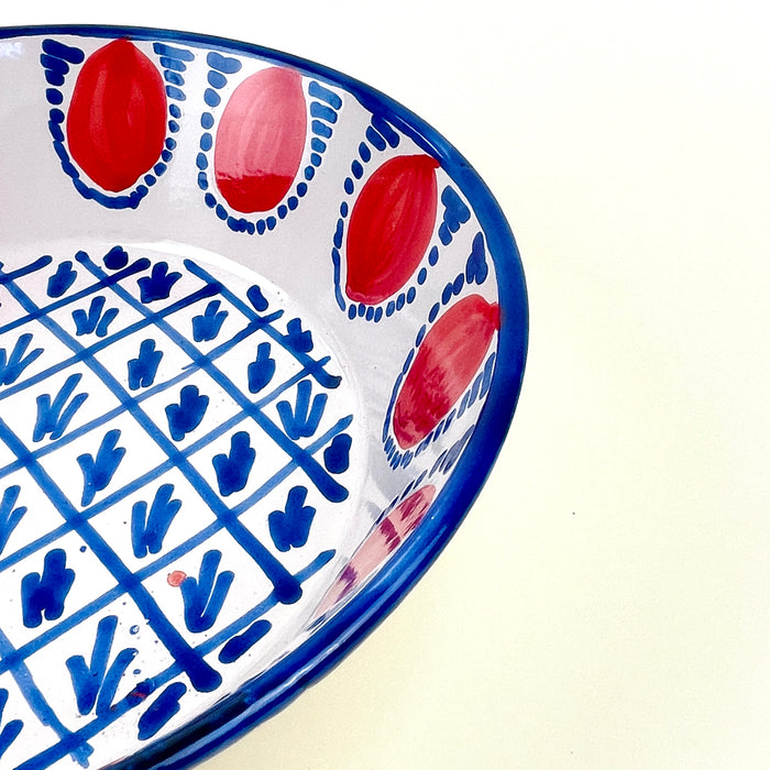 Large Spanish ceramic bowl inspired by traditional Fajalauza pottery from Granada, with red pomegranate motifs around the rim and blue hand painted geometric decoration in the basin. The cream-white glaze, rounded lebrillo form, and expressive brushwork make it suitable for wall display, fruit display, or Mediterranean table decor.