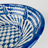 Exterior of the Granada lebrillo bowl with broad cobalt blue brush motifs sweeping across the white glaze above the exposed terracotta foot. Natural pitting, glaze variation and minor surface wear remain visible, reinforcing the handmade character of this substantial Spanish pottery serving bowl and decorative Mediterranean ceramic.